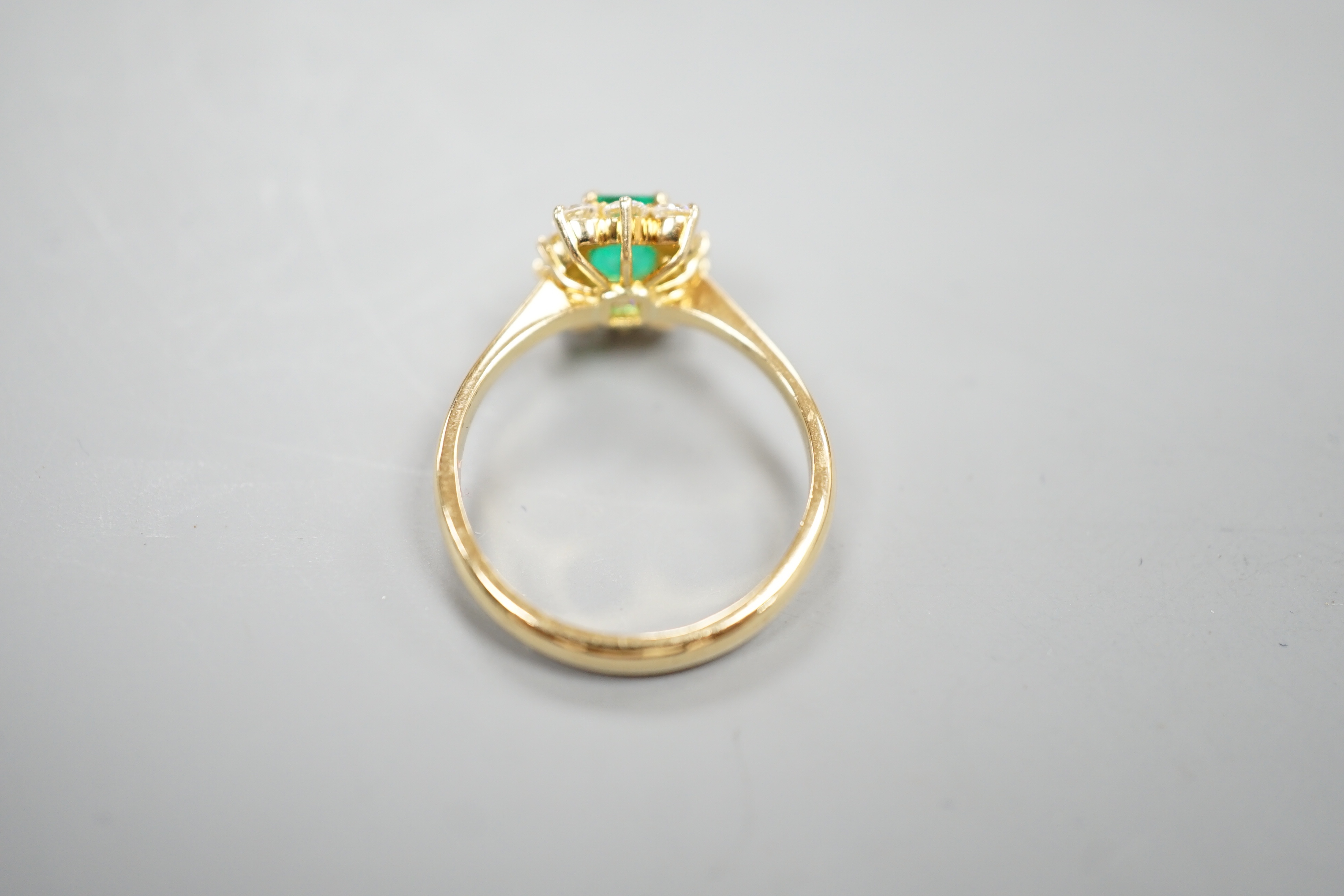 A 750 yellow metal, emerald and diamond set cluster ring, size m, gross weight 3.2 grams.